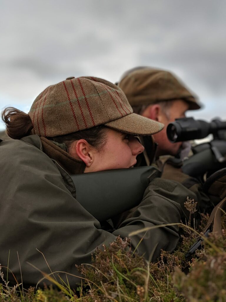 Woman holding a rifle lying down in heather
